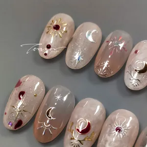 Detail of nude pink marble press-on nails with golden sun, moon, and star charms