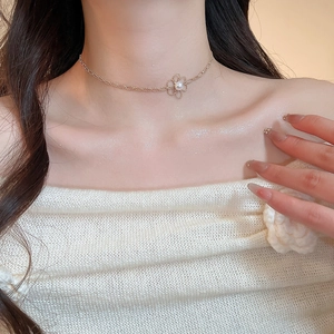 Close-up of elegant gold hollow flower pendant with a pearl inlay on a dainty chain