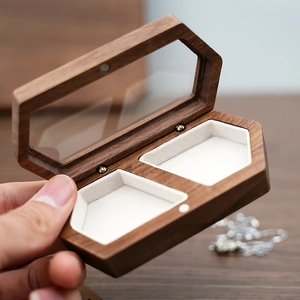 Macro detail of walnut wood jewelry box with white velvet lining and clear glass window