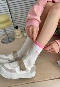 Close-up of pink striped cotton socks with bunny embroidery and Mary Jane shoes