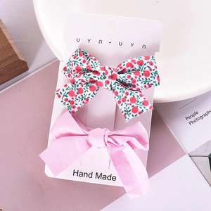 Detailed view of handmade floral and pink fabric bow hair clips on a display card