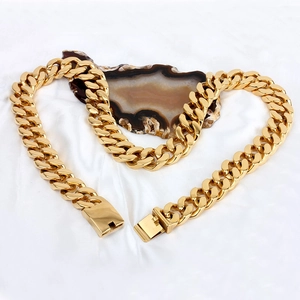 Detail view of thick gold Cuban link chain necklace with spring clasp on white silk background