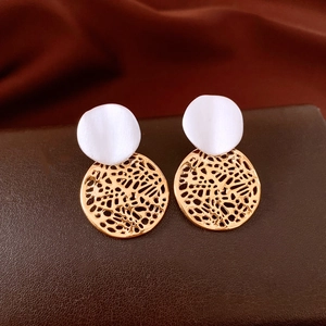Dettaglio di orecchini a cerchio vuoto placcati oro 18k con petalo in madreperla su pelle