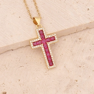 Detailed view of a gold cross pendant with red square gems and micro-set clear zircons