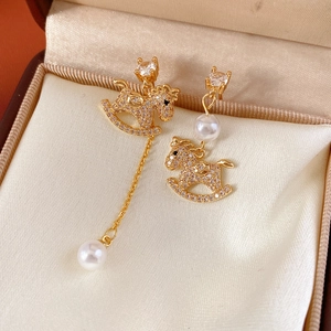 Detail of asymmetric rocking horse earrings with gold plating, pearls and tiny zircons