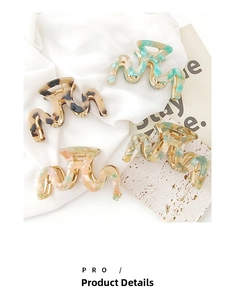 Macro detail of four acetate hair claws in tortoise, mint, pink, and yellow patterns