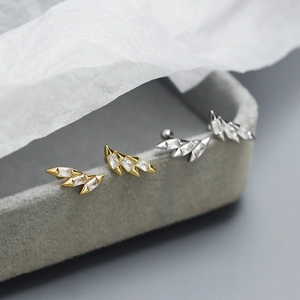 Close-up of gold and silver wing-shaped stud earrings with zircons on velvet tray