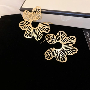 Macro shot of gold hollow filigree flower stud earrings on black velvet background