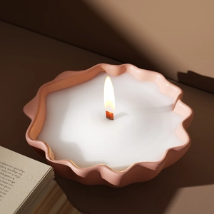 Detailed view of a pink wavy ceramic candle holder with a burning wooden wick