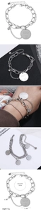 Detail of layered stainless steel bracelet with coin pendant and lobster clasp