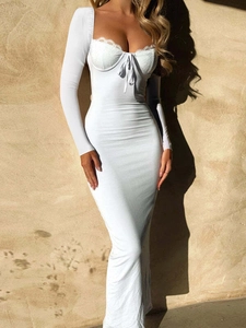 Dettaglio dell'elegante abito lungo bianco a maniche lunghe con pizzo e lacci frontali
