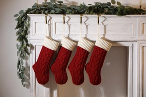 Set of four red knitted Christmas stockings hanging on a white decorated mantel