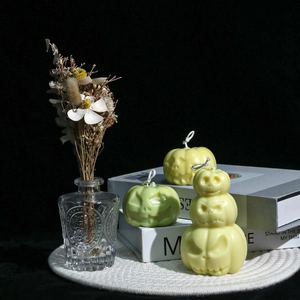 Detailed view of stacked Halloween pumpkin candles in matte pastel yellow and green colors