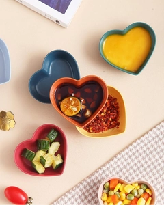 Top view of multi-colored heart-shaped sauce dishes with various food seasonings