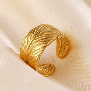Minimalist gold feather open ring with brushed metal texture on champagne silk