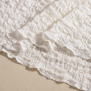 Close-up of white 3D textured lace fabric showing intricate bubble gauze details