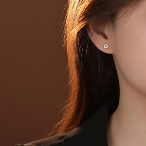 Modern S999 sterling silver coin stud earrings worn by a model in a side profile view