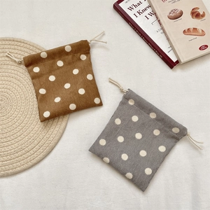 Detailed texture of brown and grey corduroy drawstring bags with classic white polka dots
