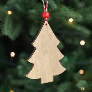 Wooden Christmas tree ornament with red beads hanging on a real festive pine branch