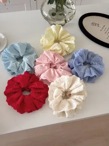 Detailed flat lay of six colorful lace eyelet embroidered scrunchies on a white desk