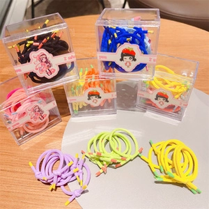 Colorful elastic hair ties set in a transparent acrylic box on a light wood background