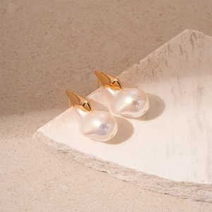 Boucles d'oreilles baroques en perles irrégulières et métal doré sur fond de pierre