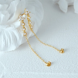 Detailed macro view of gold tassel earrings featuring diamond petal accents and butterfly back