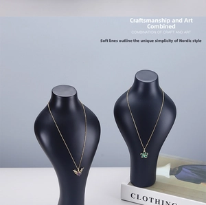 Detail view of heart and flower pendant necklaces on a black mannequin display stand