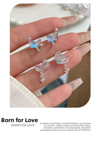 Detail shot of iridescent laser butterfly earrings with silver star charms held in hand