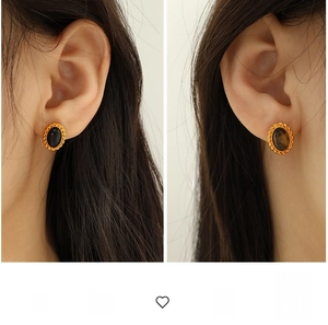Close-up of vintage oval gold stud earrings featuring brown tiger eye stone and twisted border