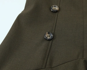 Détail macro de la robe vert olive foncé avec épaulettes et boutons effet marbre