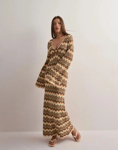 Dettaglio della trama a maglia di un abito lungo con scollo a V e motivo chevron