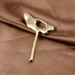 Macro shot of gold liquid metal horse brooch with organic shapes on brown satin