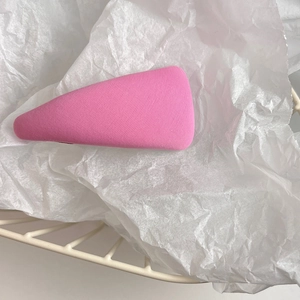 Detail of a pink triangular fabric hair clip on white tissue paper with soft lighting
