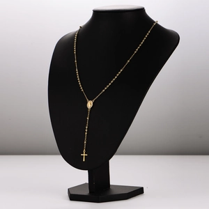 Gold rosary cross necklace with beads and oval religious medallion on a black bust
