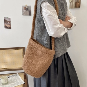 Détail d'un sac seau en peluche marron avec bandoulière large dans un décor rétro
