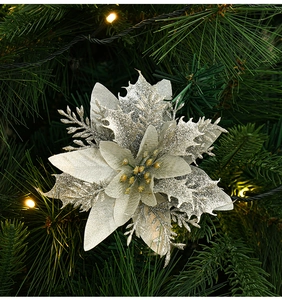 Close-up of silver glitter poinsettia with gold stamens on green Christmas tree branch