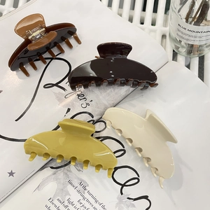 Detailansicht von vier großen Haarklammern aus Acetat in Karamell und Beige auf Magazin
