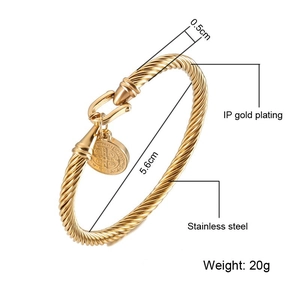 Twisted cable cuff bangle in gold stainless steel featuring a round emblem charm
