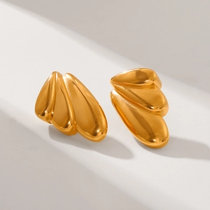 Detailed view of layered wing-shaped gold earrings with polished 18k metallic finish