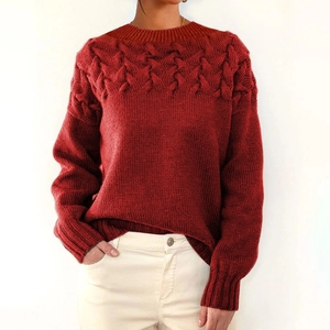 Detail of red cable knit pattern on front and sleeves of this long sleeve sweater