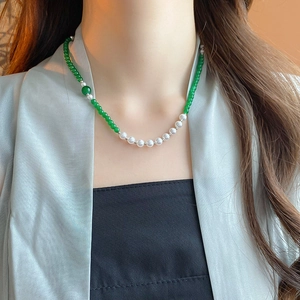 Detail of emerald beads and pearl necklace worn by a model in vintage Chinese style