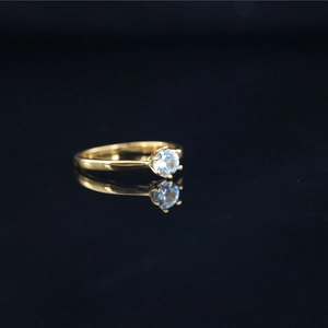 Minimalist gold moissanite solitaire ring with four-prong setting on black background