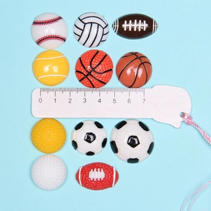Detailed size comparison of resin sports ball charms using a wooden scale ruler