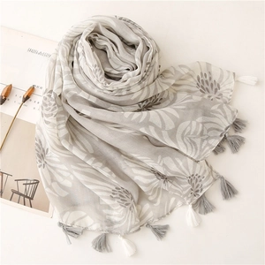 Détail d'une écharpe gris clair à imprimé floral avec franges et texture lin doux