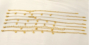 Close-up of 18K gold-plated double-layer heart anklets and pearls on white fabric