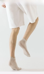 Detail of light beige low-cut cotton socks with elastic ribbed cuffs on a clean model