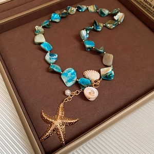 Detail of seashell necklace featuring turquoise chips, pearls and a golden starfish