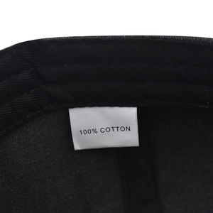 Detail shot showing the 100% cotton material tag on a black washed vintage baseball cap