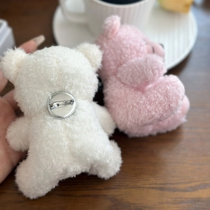 Detail showing the metal safety pin attachment on the back of a plush bear brooch